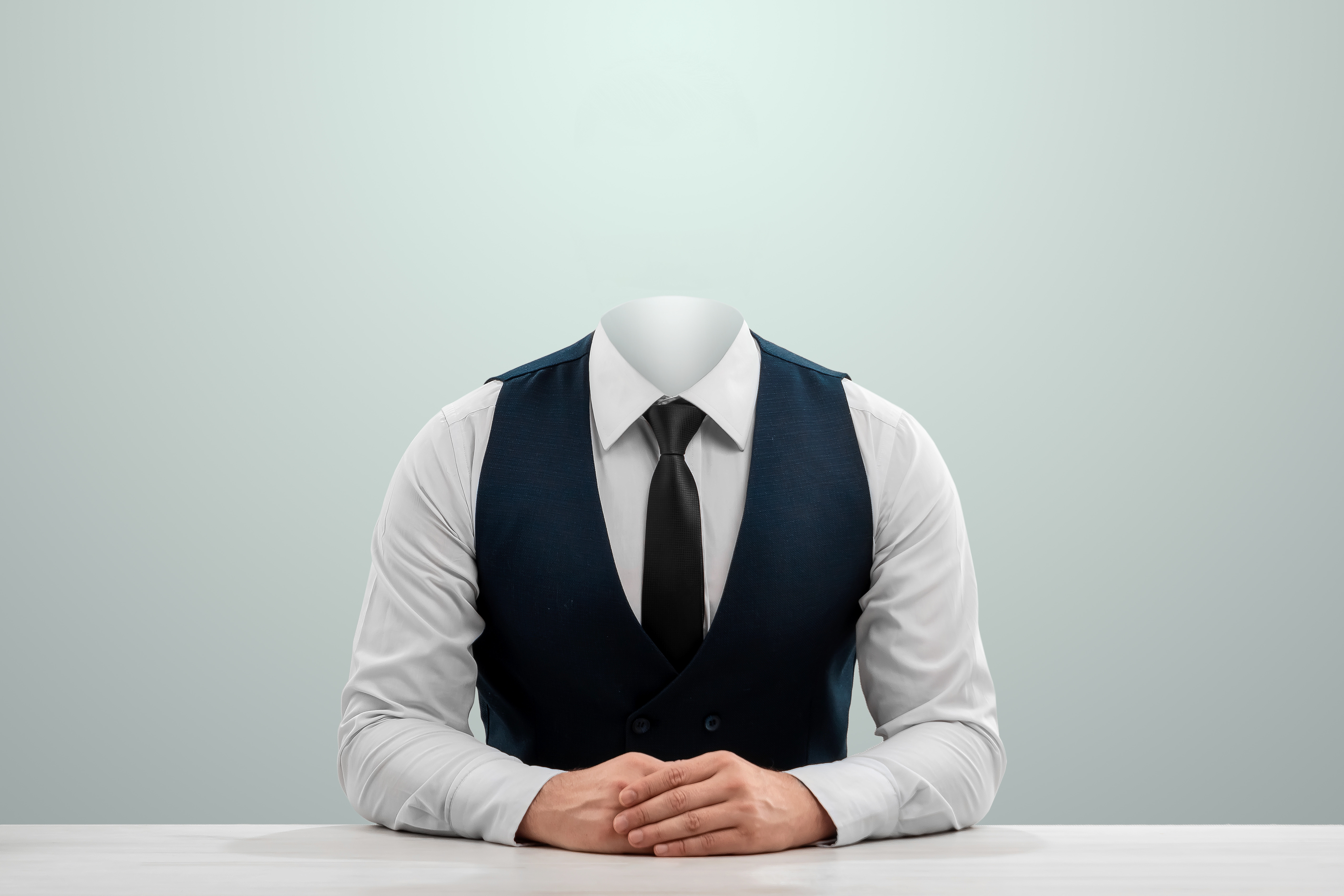 Headless person wearing a suit and sitting at a table